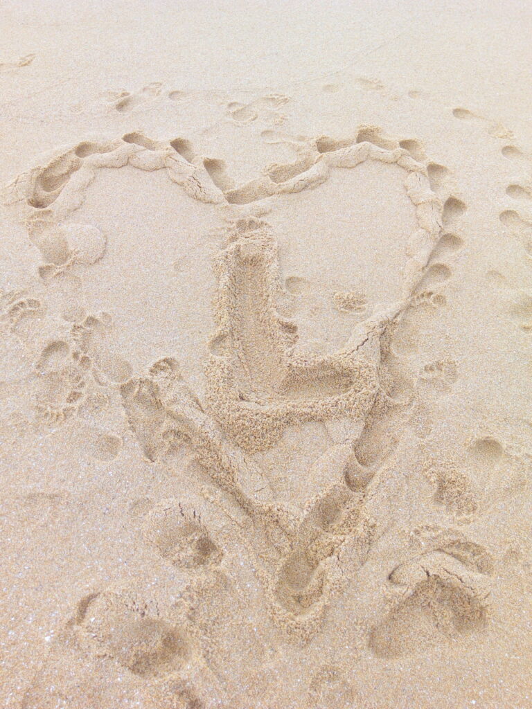 Un coeur dessiné dans le sable avec un L au milieu