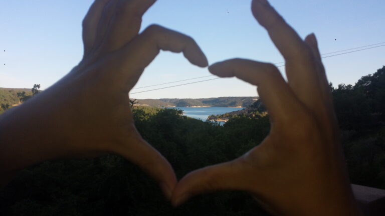 une personne qui fait un coeur avec ses mains sur un arrière plan du lac des gorges du Verdon