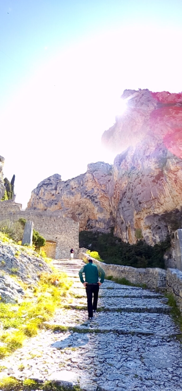 Photo en contre jour d'une personne qui monte un escalier en pierre en pente douce entre les montagnes