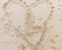 Un coeur dessiné dans le sable avec un L au milieu