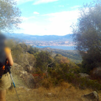 Photo de la mer et des rochers en premier plan pris d'un chemin en hauteur en Corse