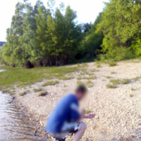 Photo d'une personne agenouillé sur un plage sur le bord d'un lac qui semble sortir d'un bateau et découvrir cette plage