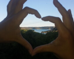 une personne qui fait un coeur avec ses mains sur un arrière plan du lac des gorges du Verdon